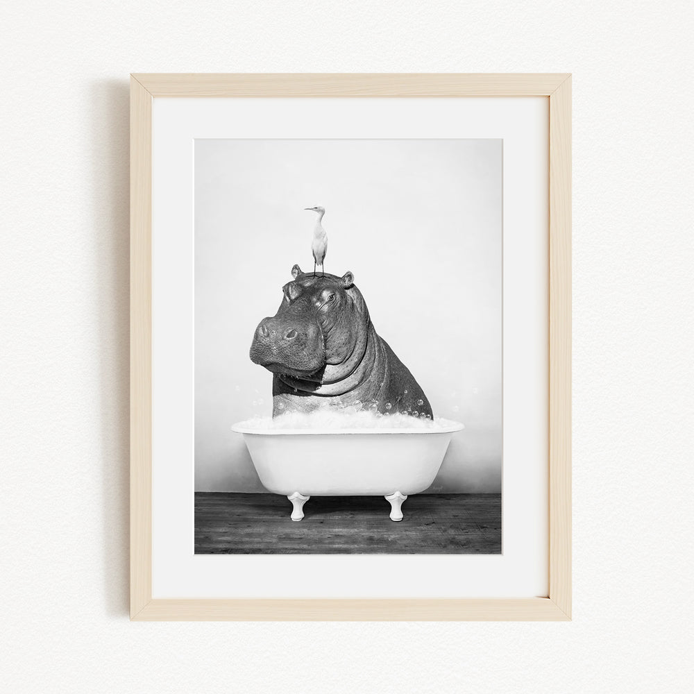 A black and white photograph of a hippopotamus sitting in a bathtub, with a bird perched on its head.