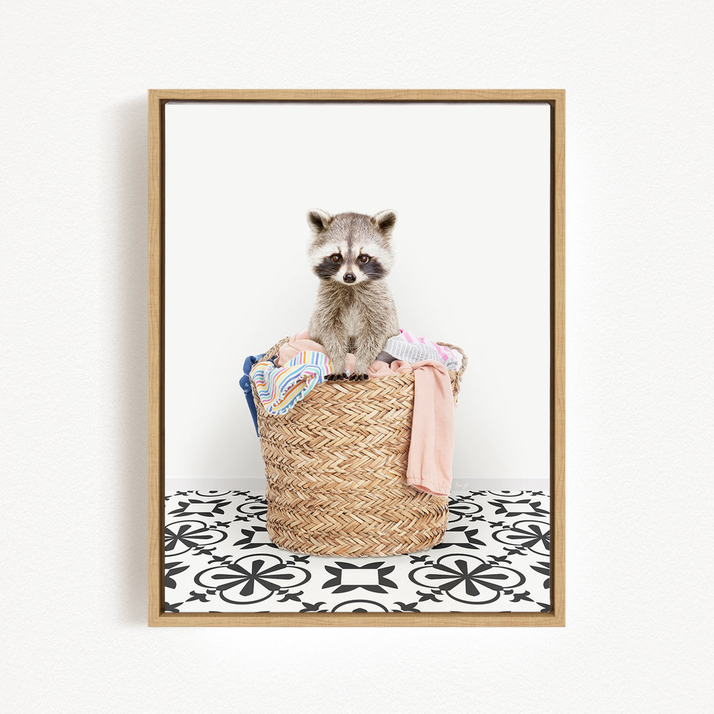 A raccoon sitting in a woven basket filled with clothes and towels.