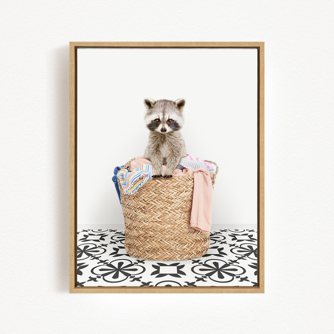 A raccoon sitting in a woven basket filled with clothes and towels.