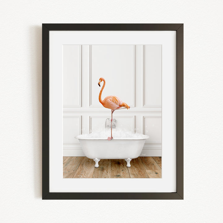 A framed image of a flamingo standing on the edge of a white bathtub filled with water.