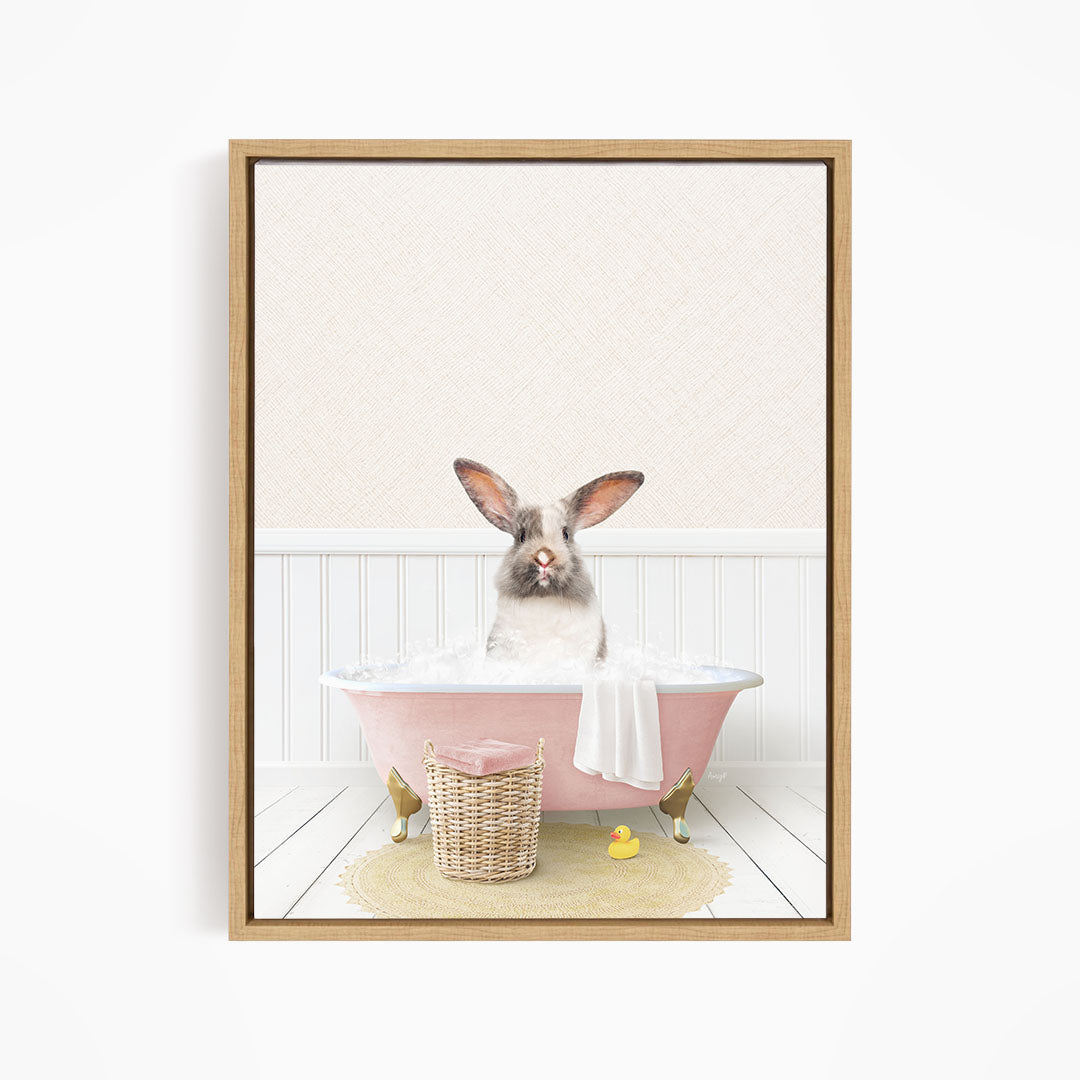 A fluffy white rabbit sits in a pink bathtub filled with bubbles, surrounded by a yellow rubber duck and a basket.