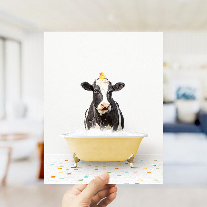 A black and white cow is sitting in a yellow bathtub filled with bubbles, with a yellow rubber duck perched on its head.