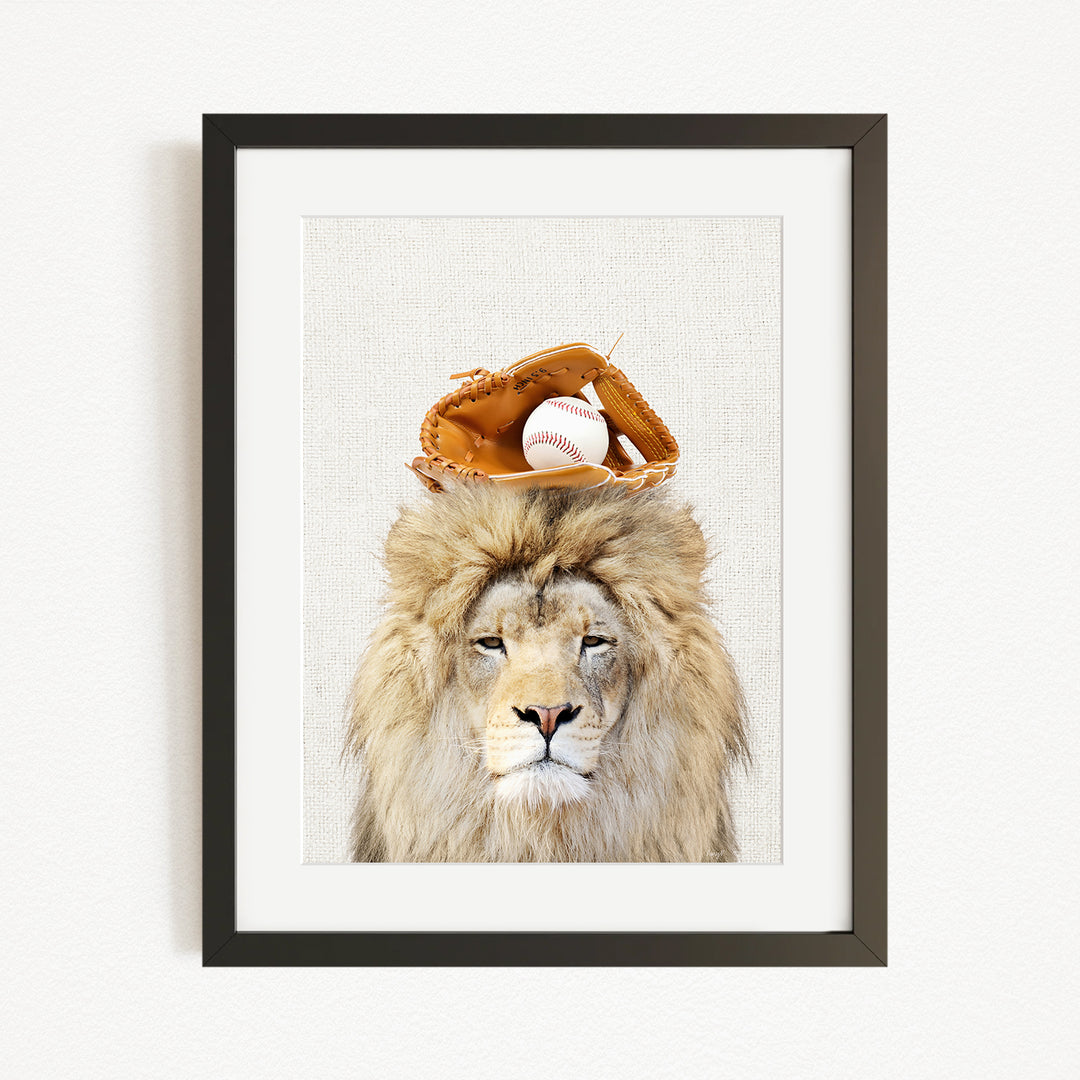 A framed image of a lion wearing a baseball glove on its head, with a baseball resting on top of the glove.