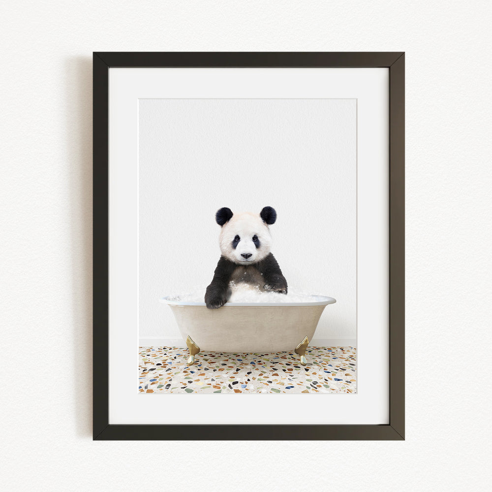 A panda bear sitting in a white bathtub filled with bubbles, looking directly at the camera.