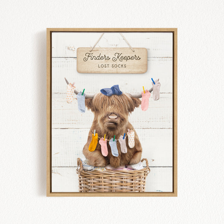 A brown cow with long hair sits in a wicker basket, wearing a blue bow and surrounded by colorful socks hanging from clotheslines.
