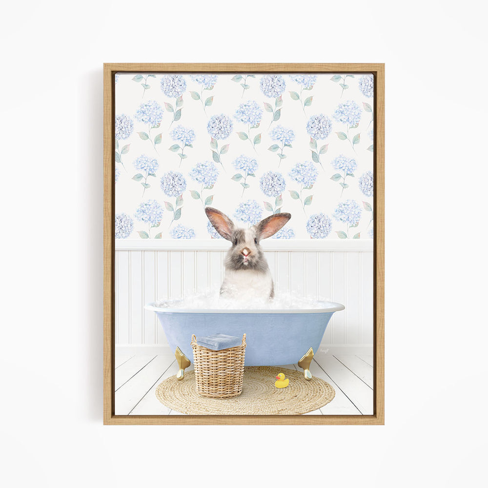 A rabbit sitting in a blue bathtub filled with water, surrounded by a wicker basket and rubber duckies.