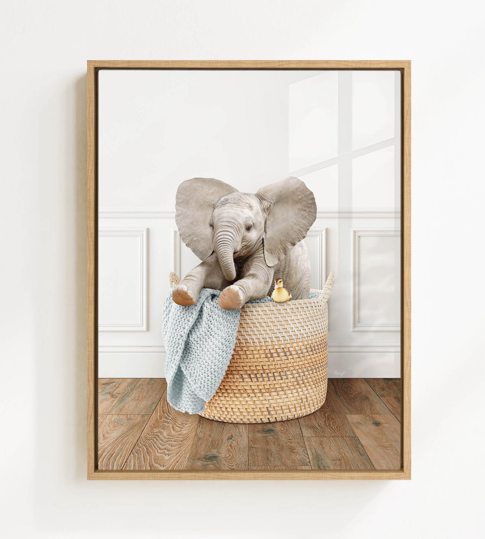 A baby elephant sitting in a woven basket, with a blue blanket and a small yellow bird nearby.