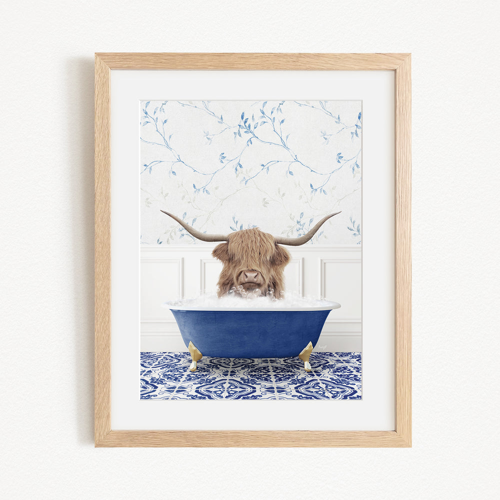 A brown cow with long horns is sitting in a blue bathtub, surrounded by a blue and white patterned rug and a white wall with blue floral wallpaper.