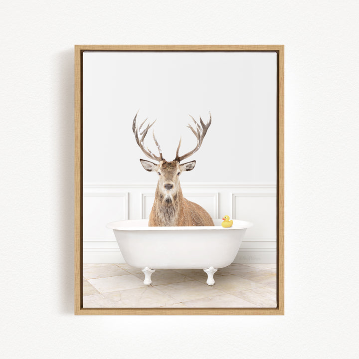 A deer with antlers is sitting in a white bathtub, with a rubber duck floating in the water.