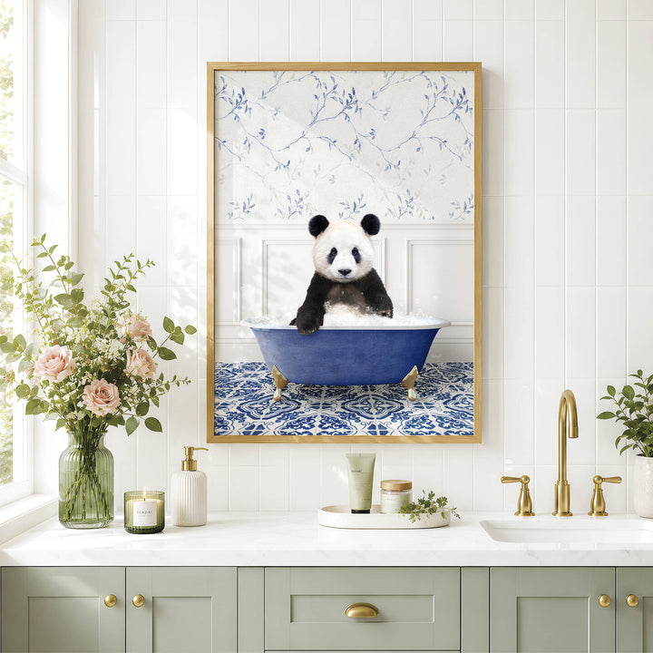 A framed image of a panda sitting in a blue bathtub is displayed on a white wall above a bathroom counter with various toiletries and a vase of flowers.