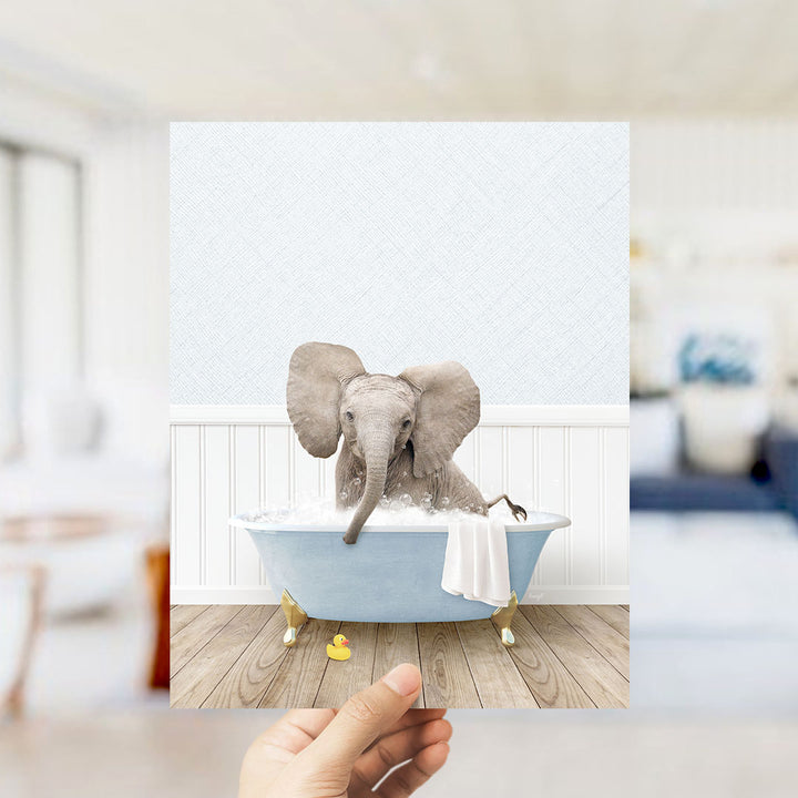 A small elephant sitting in a blue bathtub filled with water, surrounded by a white towel and a rubber duck.