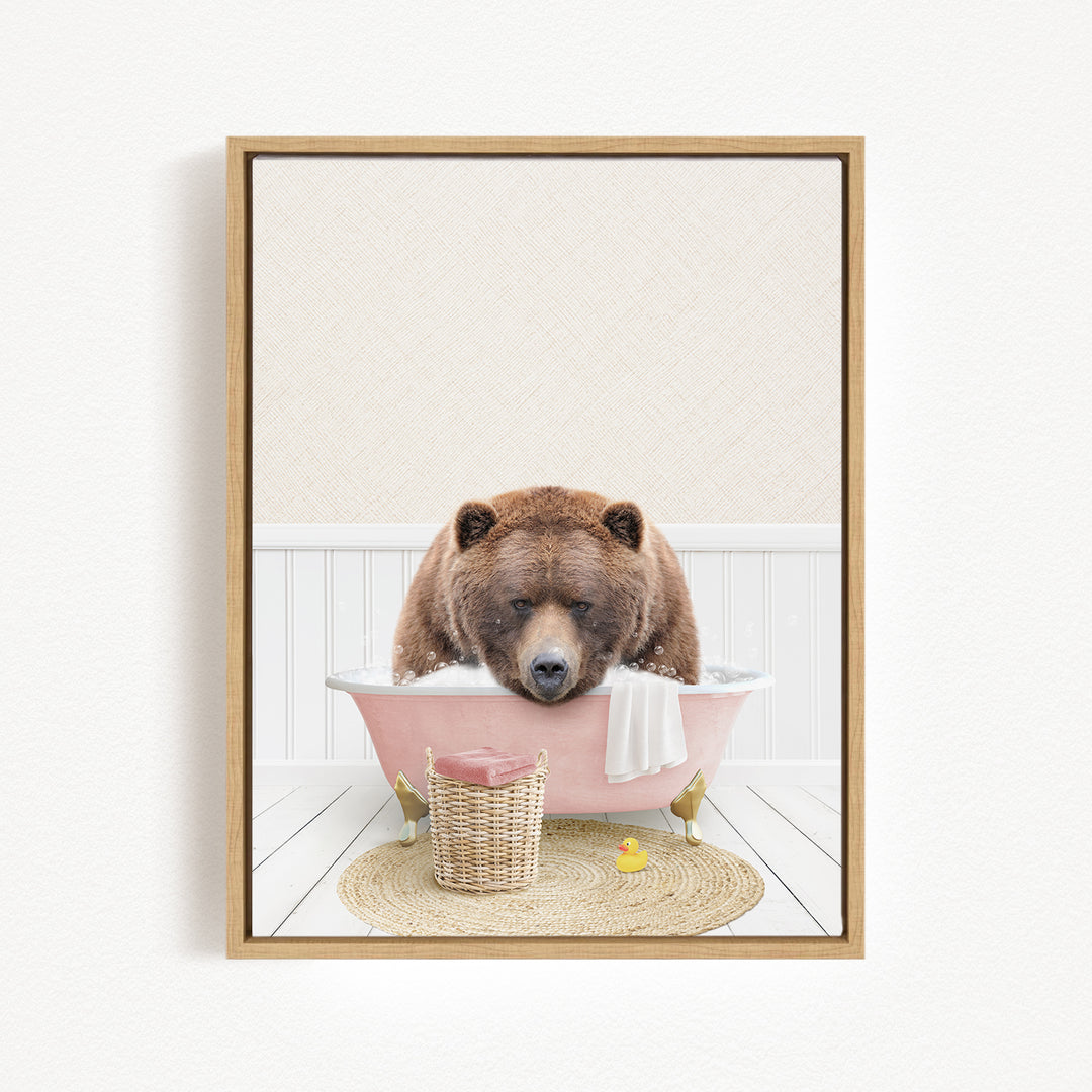 A brown bear is sitting in a pink bathtub, surrounded by a basket of bath toys and a yellow rubber duck.