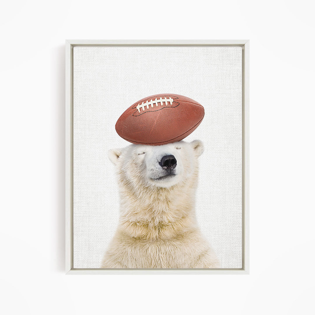 A polar bear balancing a football on its head.