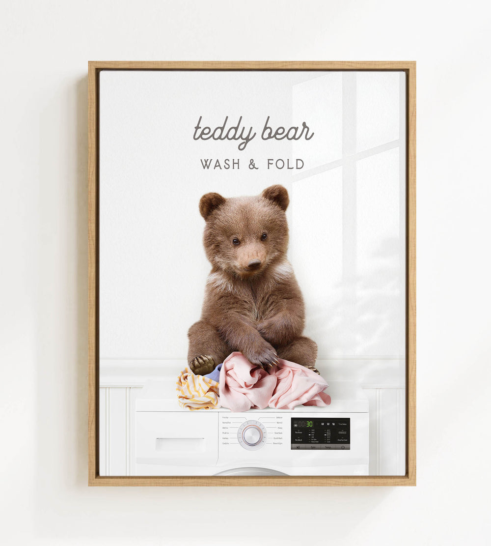 A teddy bear sitting on a pile of laundry, with the text "teddy bear WASH & FOLD" displayed above the bear.