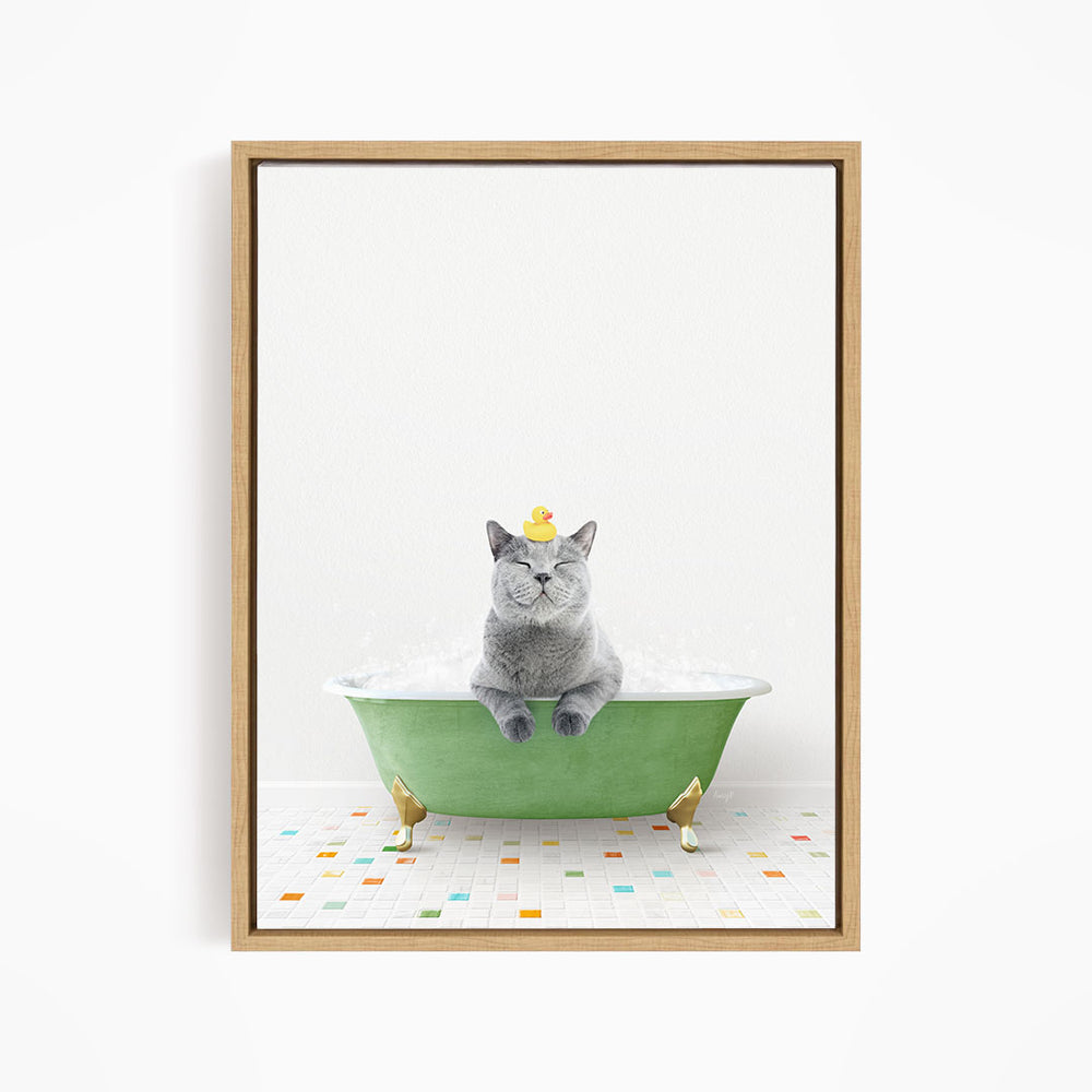 A gray cat sitting in a green bathtub, with a yellow rubber duck perched on its head.