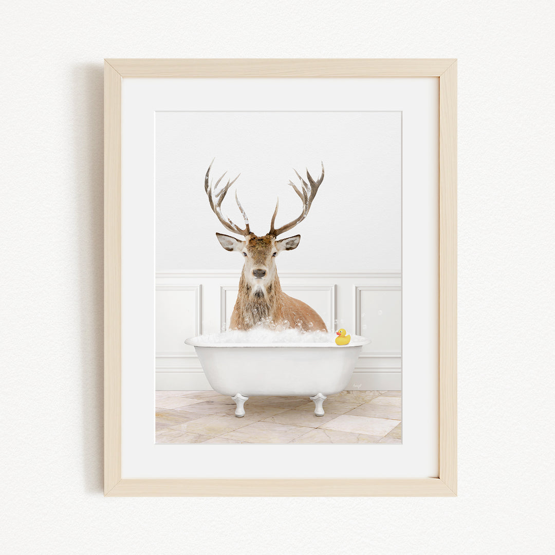 A deer with large antlers is sitting in a white bathtub filled with water, with a yellow rubber duck floating in the water.