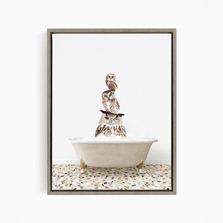 A framed image depicting three owls sitting in a bathtub, with one owl perched on top of the other two.