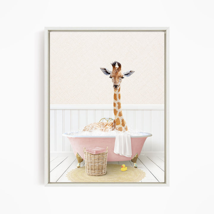 A giraffe is sitting in a pink bathtub filled with water, surrounded by a yellow rubber duck and a wicker basket.