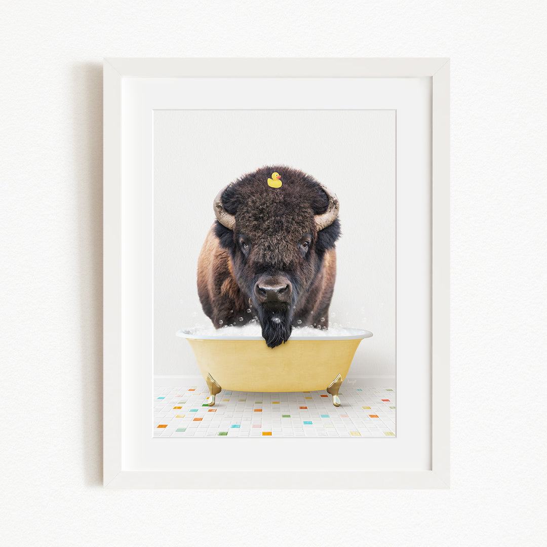 A buffalo with a yellow rubber duck perched on its head is sitting in a yellow bathtub, surrounded by a colorful tiled floor.
