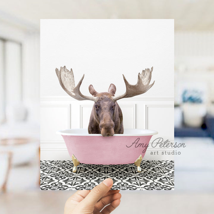 a person holding up a card with a moose head in a bathtub