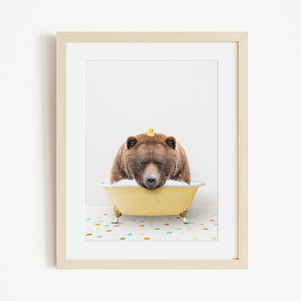 A brown bear is sitting in a yellow bathtub, with a rubber duck perched on its head.