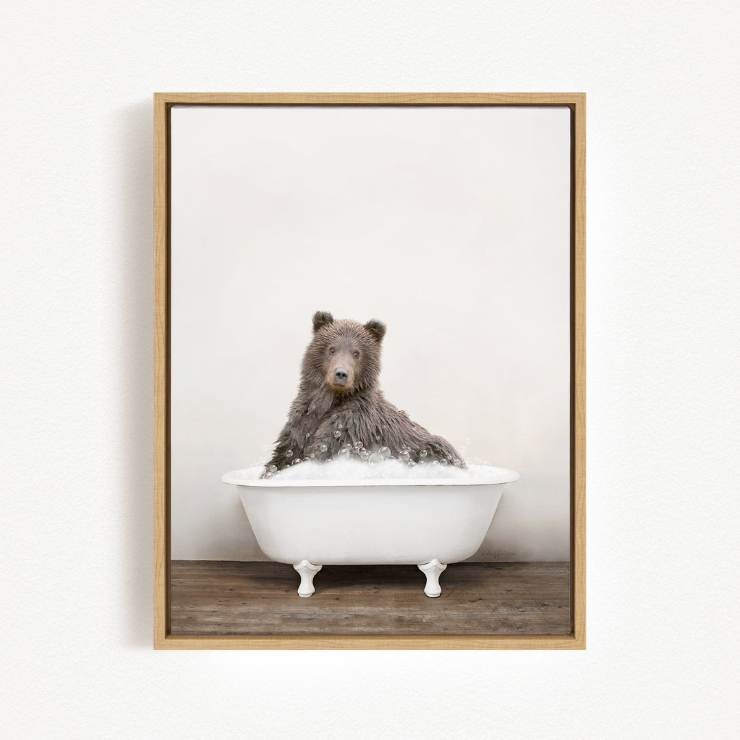 A brown bear sitting in a white bathtub filled with bubbles, looking directly at the camera.