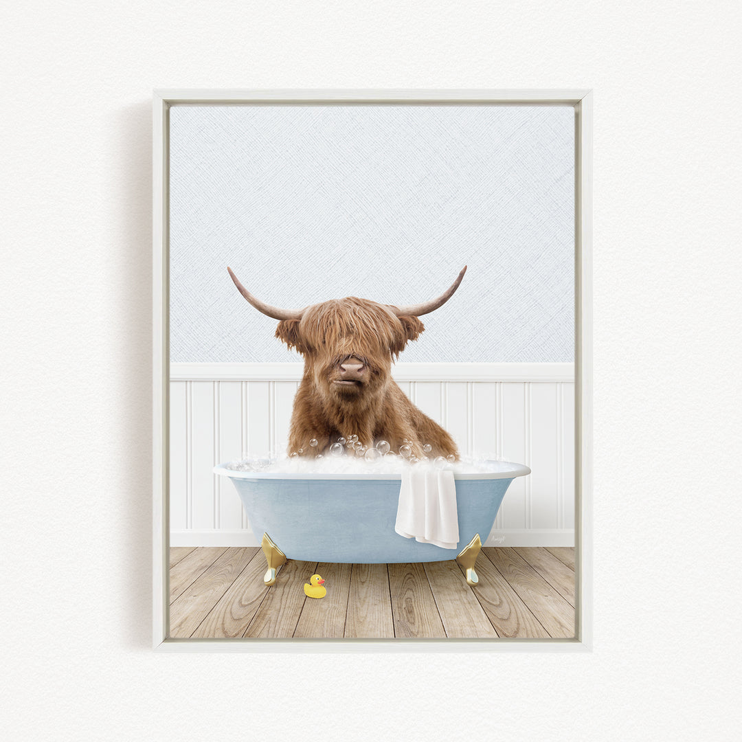 A Highland cow with long horns is sitting in a blue bathtub filled with bubbles, surrounded by rubber duckies.
