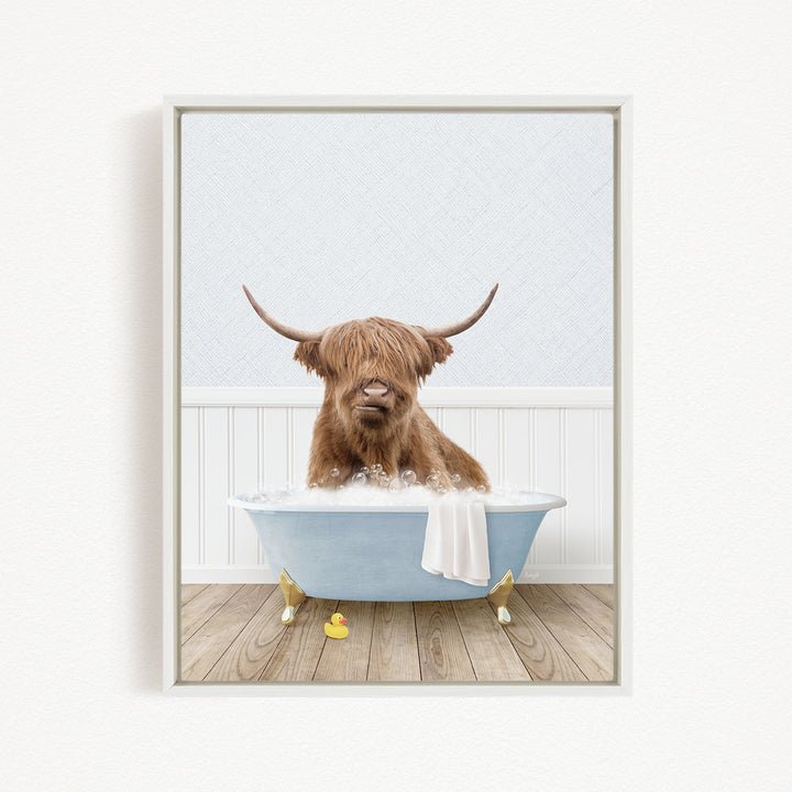 A Highland cow with long horns is sitting in a blue bathtub filled with bubbles, surrounded by rubber duckies.