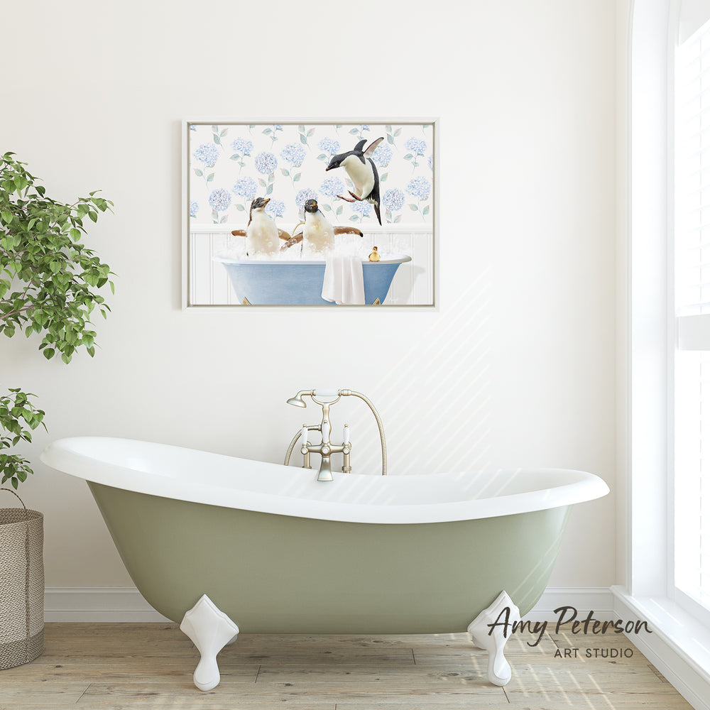 A framed image of two penguins sitting in a bathtub is displayed on the wall above a green clawfoot bathtub in a bathroom.