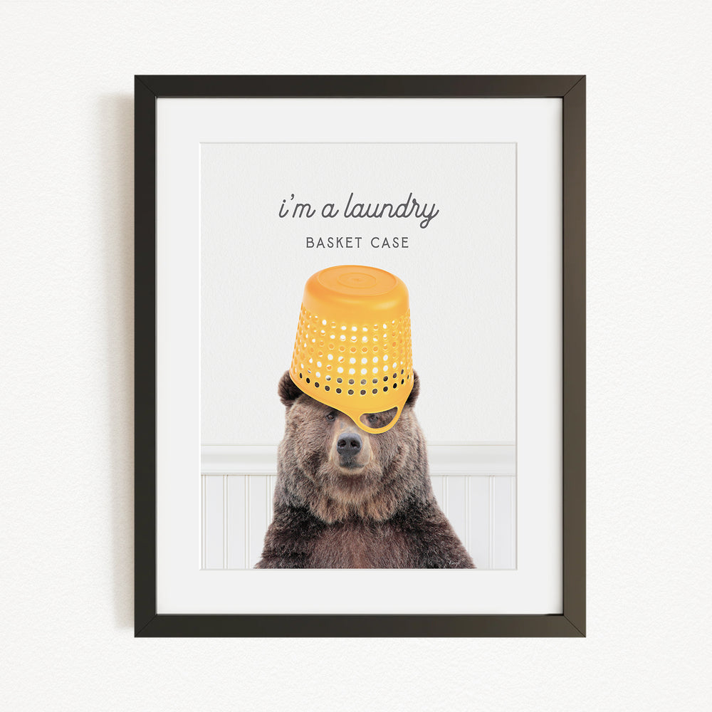 A framed image of a bear wearing a yellow basket on its head, with the text "I'm a laundry basket case" above it.