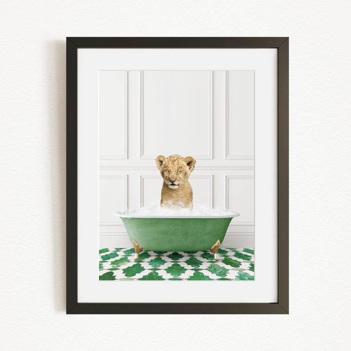 A young lion cub is sitting in a green bathtub filled with water, looking directly at the camera.