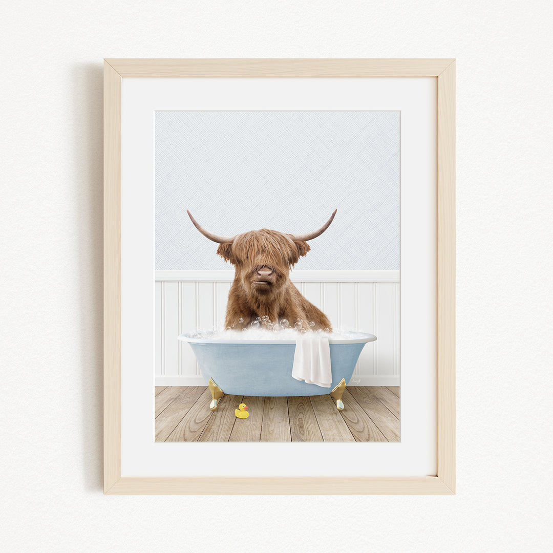 A brown cow with long horns is sitting in a blue bathtub, surrounded by yellow rubber duckies.