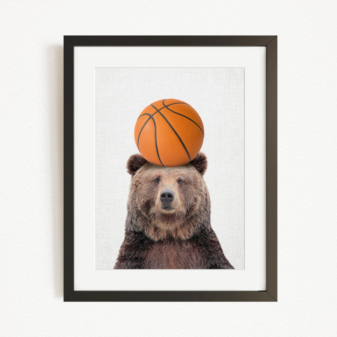 A brown bear balancing a basketball on its head.