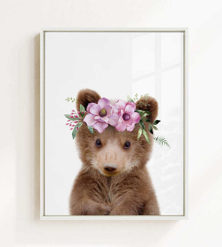 A cute brown bear wearing a floral crown of pink flowers and greenery.