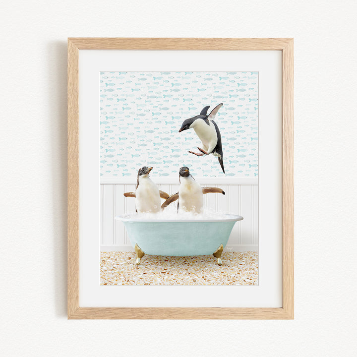 A framed image depicting two penguins sitting in a bathtub, with one penguin flying towards the other.
