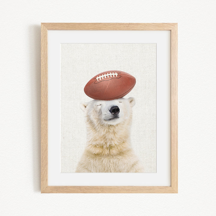 A polar bear wearing a football helmet and balancing the ball on its head.