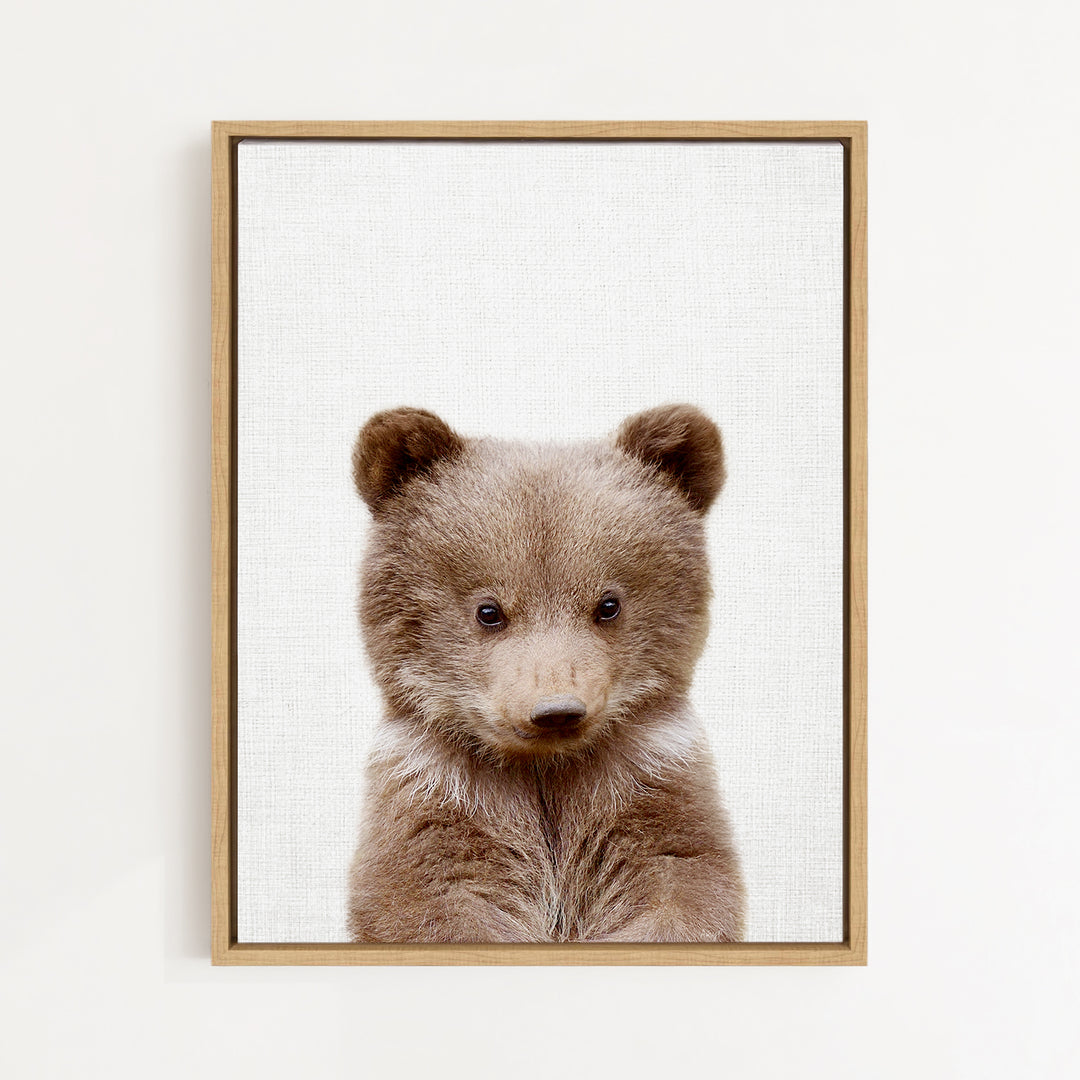 A framed print of a cute brown bear with large eyes and a curious expression, set against a plain white background.