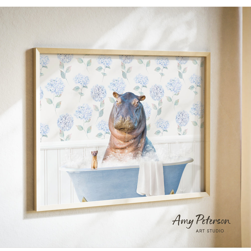 A framed image depicting a hippopotamus sitting in a bathtub, surrounded by blue flowers and a small figurine.