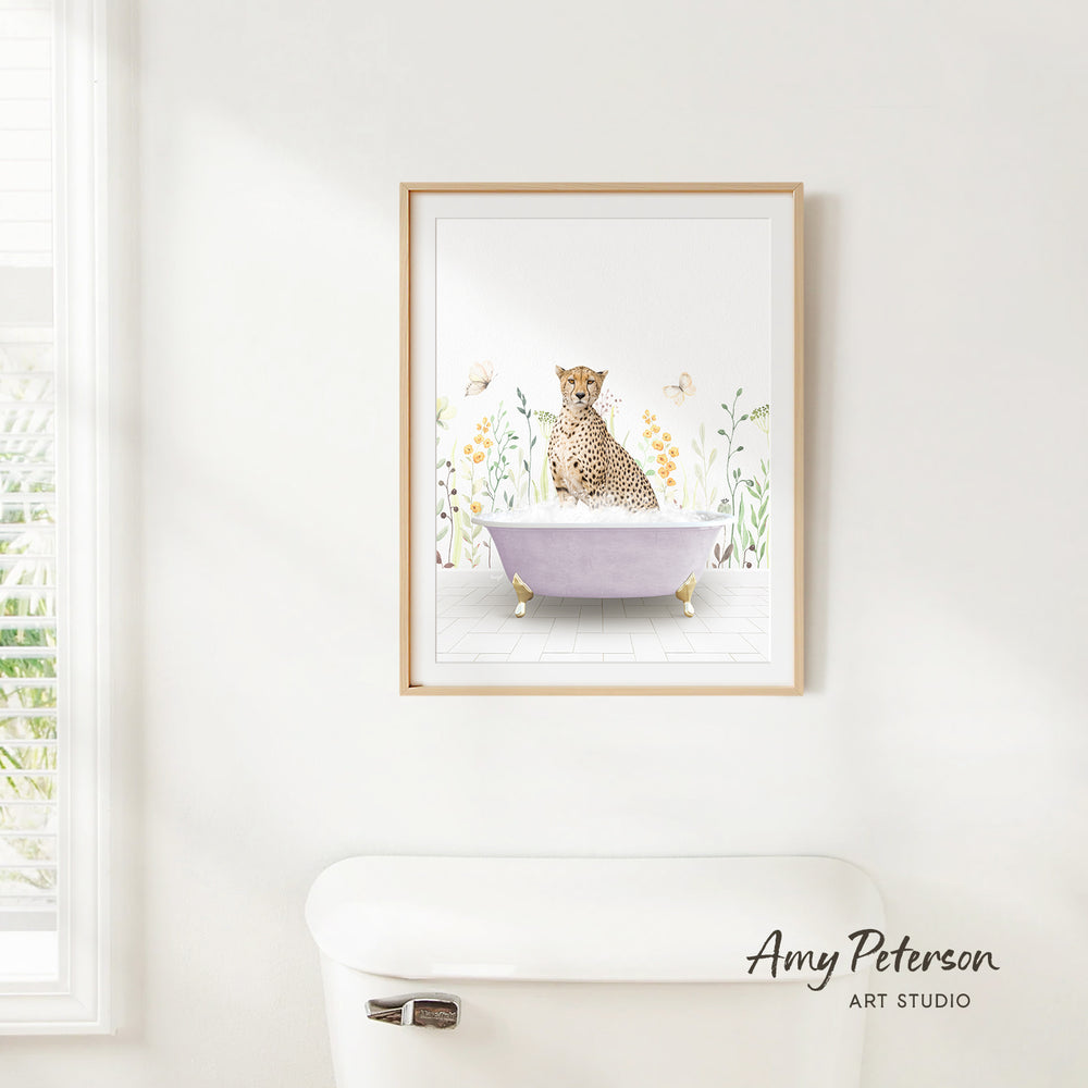 A framed print of a cheetah sitting in a bathtub is hanging on a white wall above a white toilet.