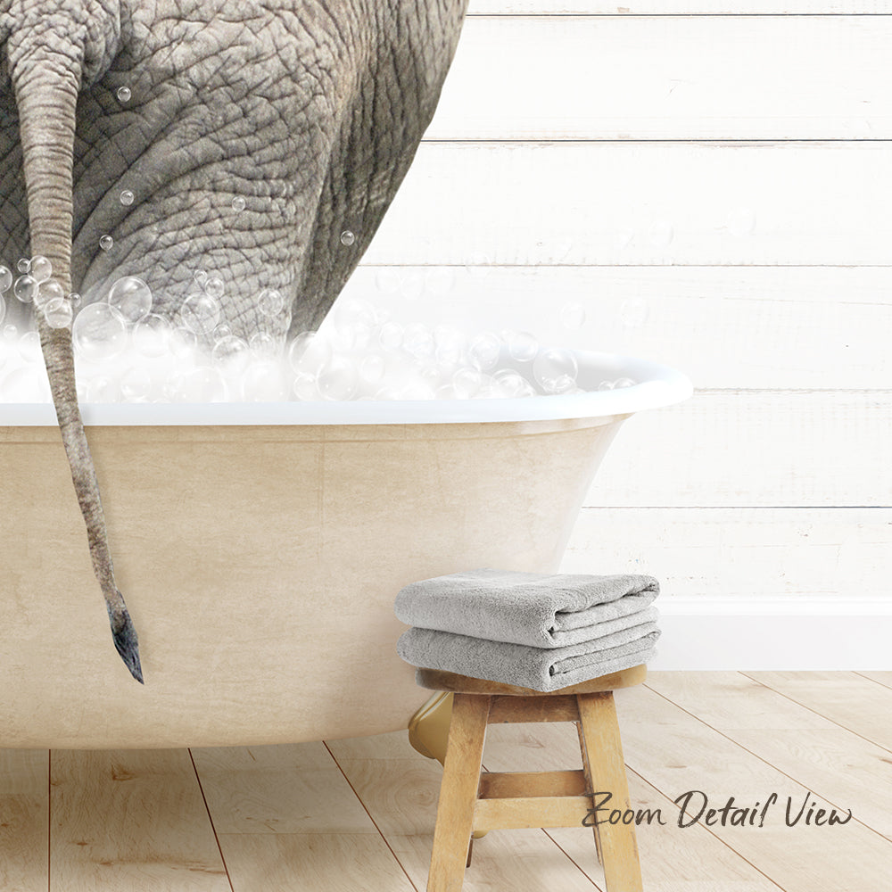A large elephant is partially submerged in a bathtub filled with bubbles, with a towel and stool nearby.