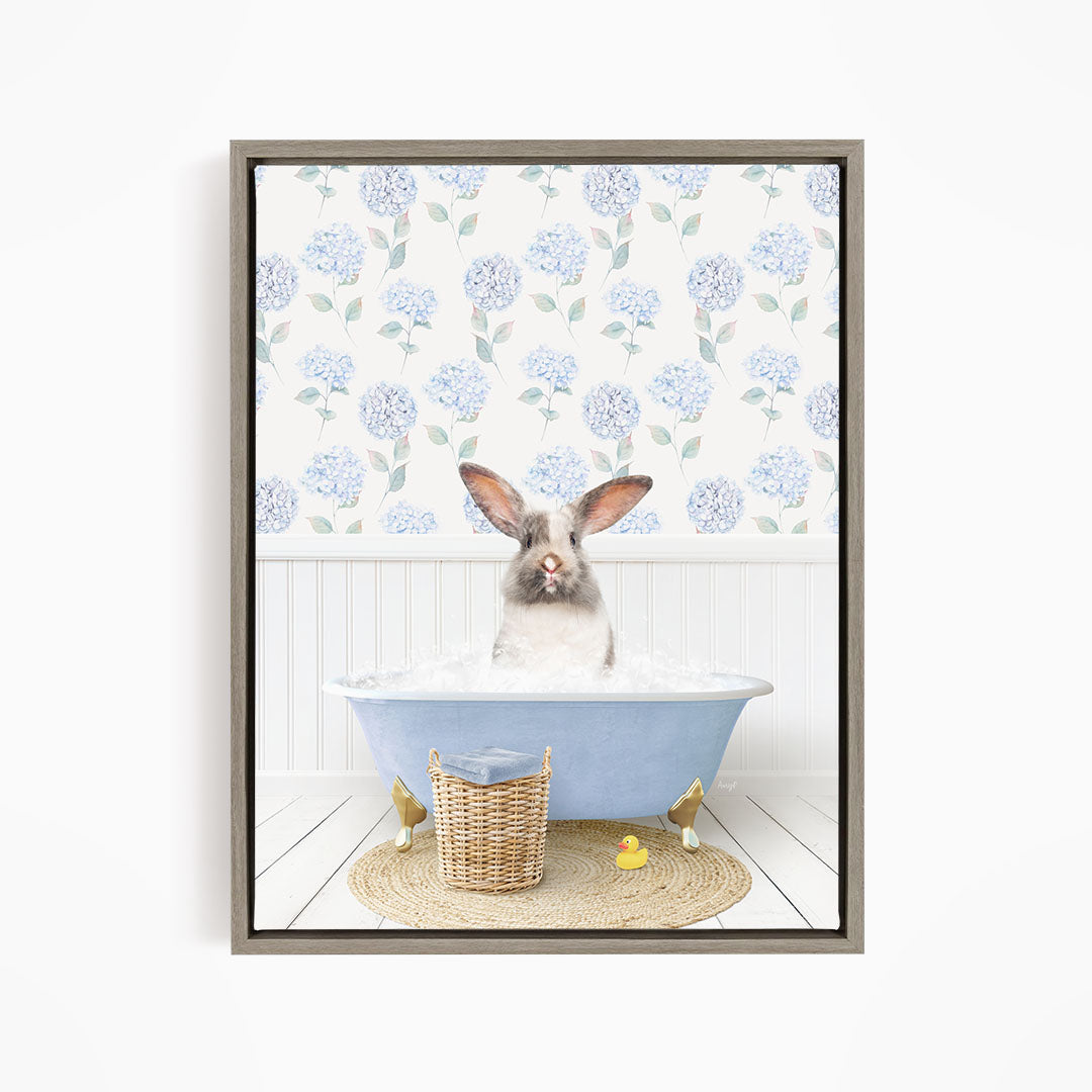 A rabbit sitting in a blue bathtub filled with water, surrounded by a wicker basket and yellow rubber ducks.