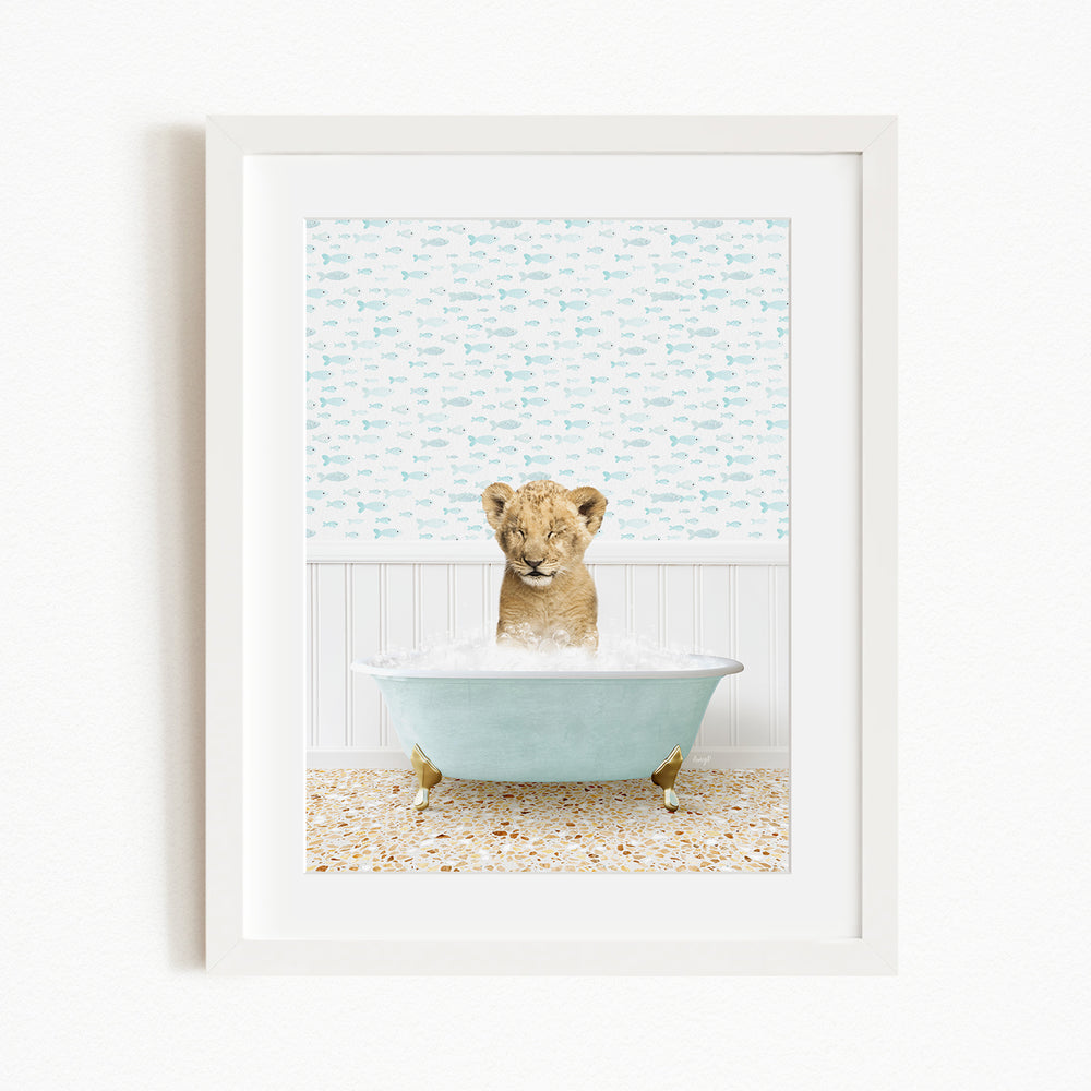 A young lion cub sitting in a blue bathtub filled with water, surrounded by a patterned wall and floor.