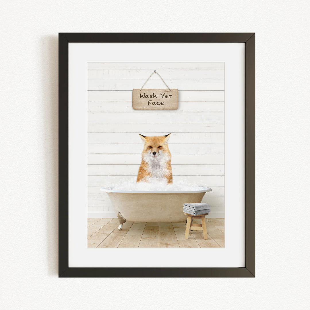 A framed image depicting a fox sitting in a bathtub, with a sign above that reads "Wash Your Face".