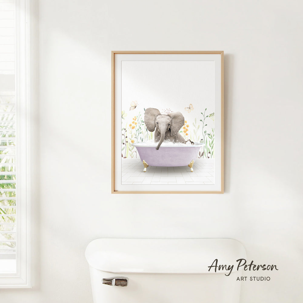 A framed illustration of an elephant sitting in a bathtub, surrounded by flowers and butterflies, is hanging on a white wall.