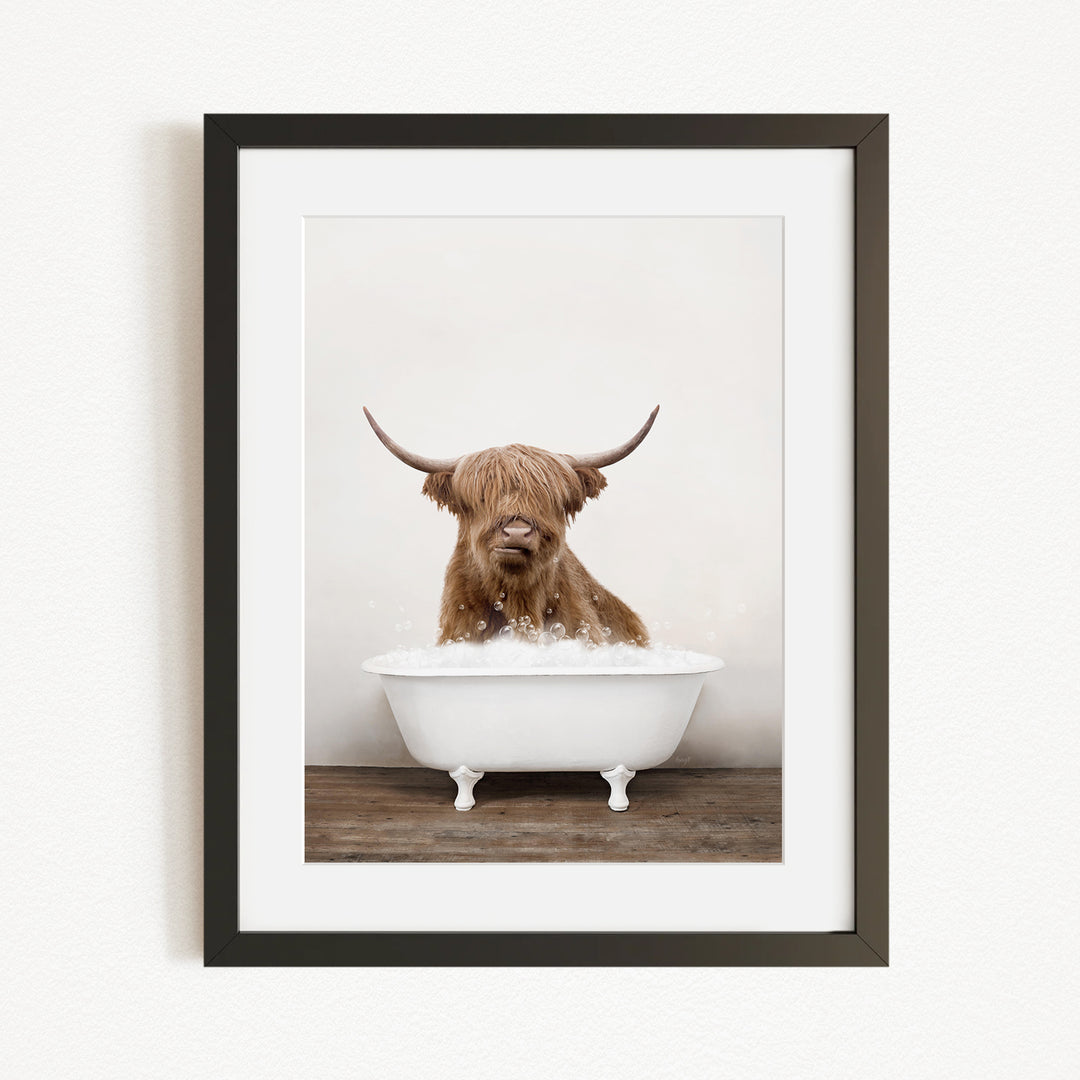 A brown cow with long horns is sitting in a white bathtub filled with water, creating a whimsical and playful scene.