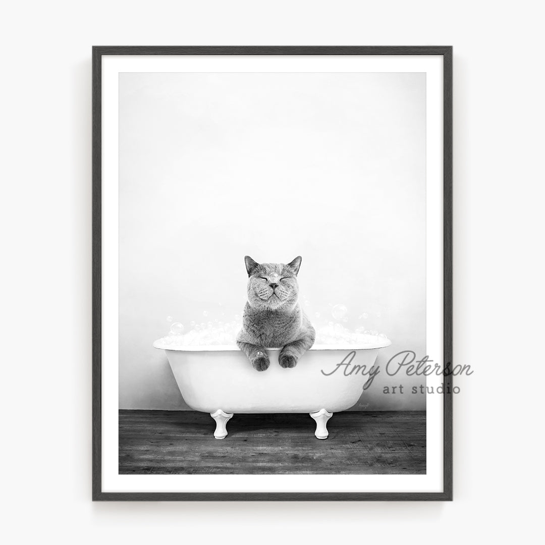 a black and white photo of a cat sitting in a bathtub