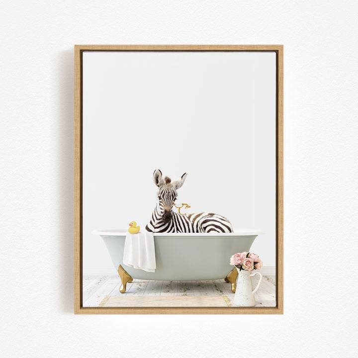 A zebra is sitting in a bathtub, surrounded by a yellow rubber duck, a white towel, and a vase of pink flowers.
