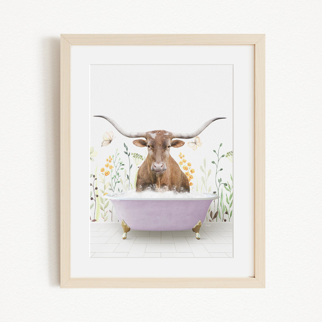A framed print depicting a brown cow with large horns sitting in a purple bathtub filled with water, surrounded by flowers and plants.