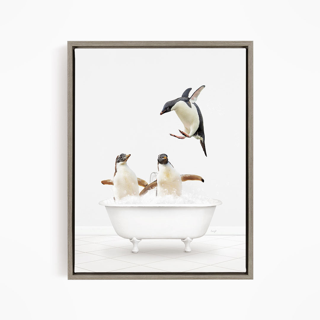 A framed image depicting three penguins sitting in a white bathtub filled with water, with one penguin flying towards the tub.