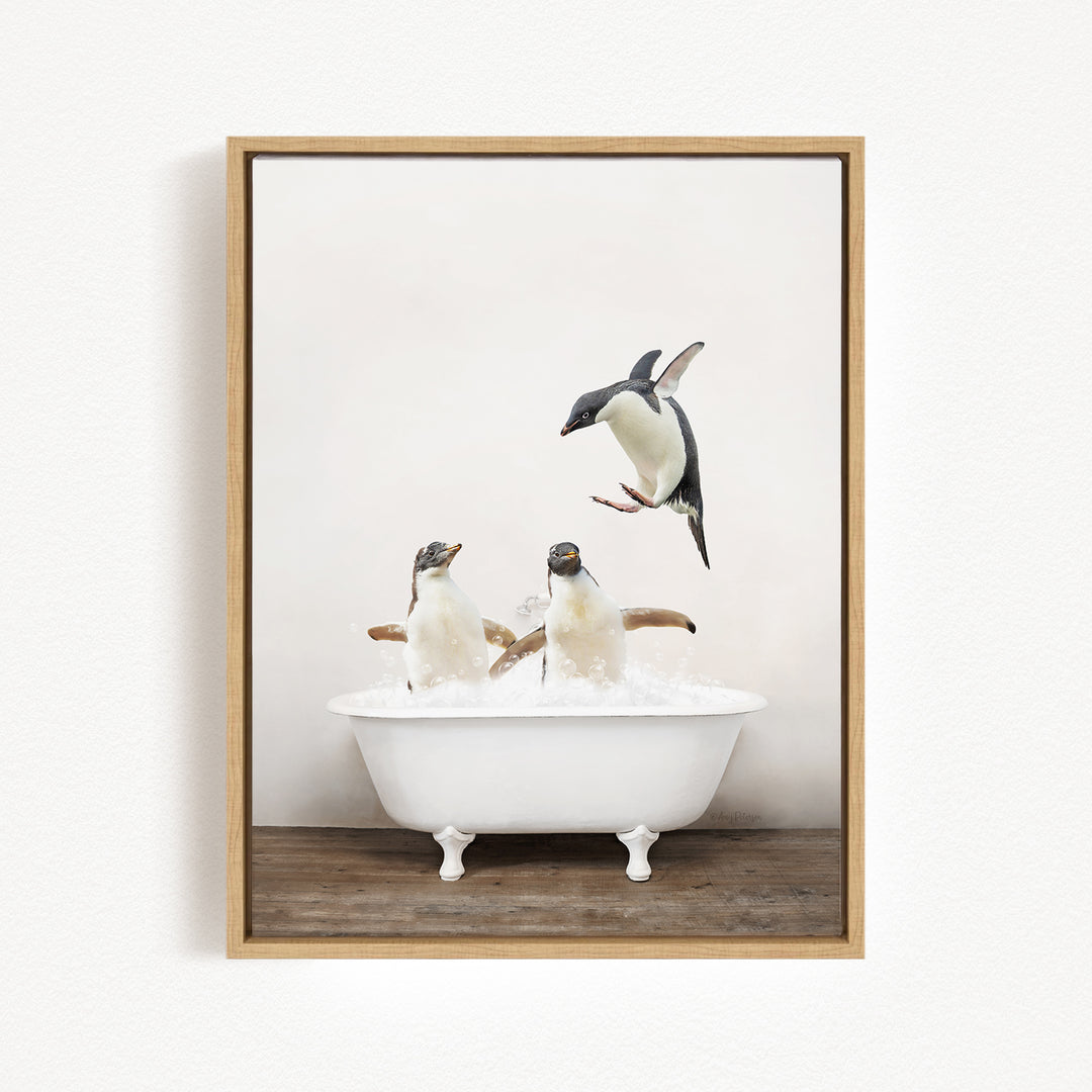 A framed image depicting three penguins in a white bathtub, with one penguin flying above the tub.